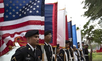 A joint color guard stands in front of flags
