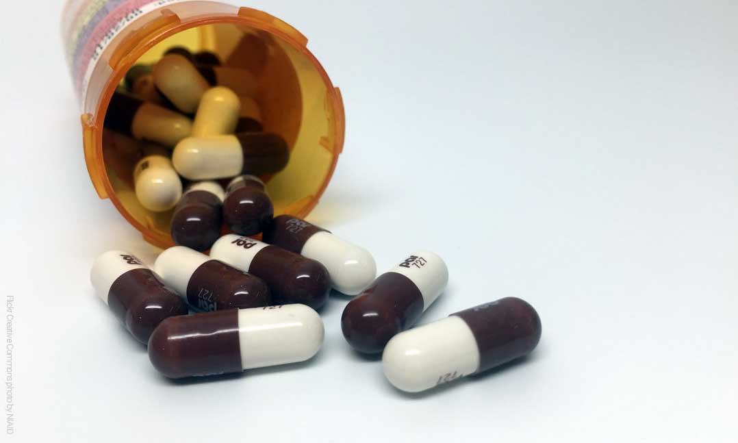 Tipped over pill bottle with maroon and white pills spilling out